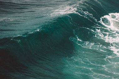 Beyaz bir köpükle bir dalga kopmaya başlar.