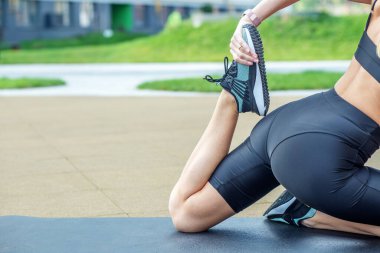 Genç kadın spor yapıyor ve şehirde bir spor sahasında geriniyor..