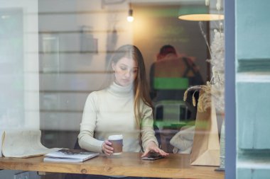 Kafedeki masada oturan genç bir kadın.