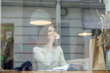 Kafede kahve içen genç bir kadın.