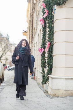 Sokakta poz veren palto ve fularlı güzel bir kadın.