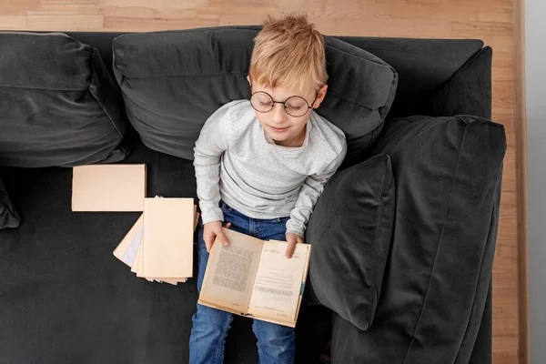 Child Reads Book Eyeglasses While Sitting Sofa Room Schoolboy Studies — Stock Photo, Image