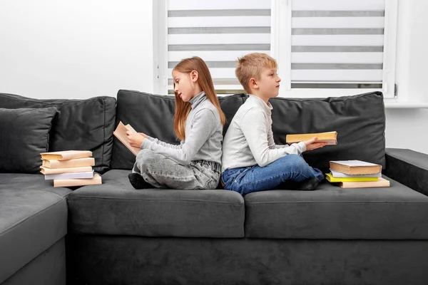 子供たちは部屋のソファに座って眼鏡で本を読みます 兄と妹は宿題を勉強している スペースのコピー — ストック写真