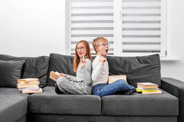 子供たちは部屋のソファに座って眼鏡で本を読みます ワールドブックデー ライフスタイル 教育のための概念 兄と妹は宿題を勉強している — ストック写真