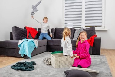 Üç çocuk odada eğleniyor ve ortalığı dağıtıyor. Mutlu bir çocukluk. Aile kavramı.