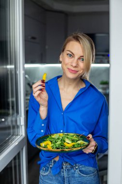 Gülümseyen genç kadın modern mutfakta taze salata hazırladı. Diyet ve sağlıklı gıda konsepti.