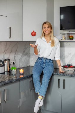 Mutfakta otururken elinde sağlıklı nar tutan gülümseyen kadın. Sağlıklı gıda, diyet ve ekolojik gıda kavramı