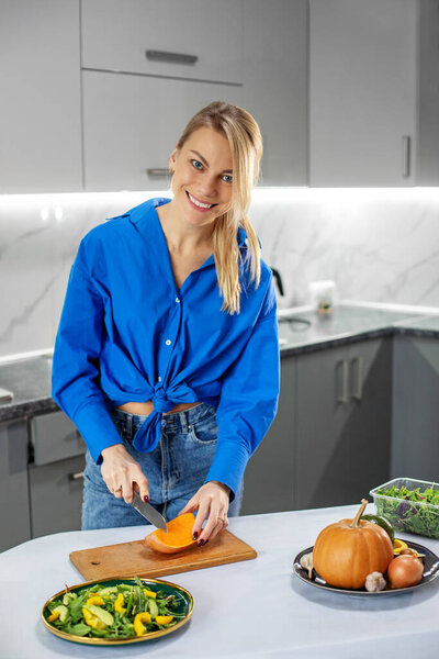 Молодая взрослая женщина готовит овощной салат на кухне. Концепция здорового питания, диеты и эко-питания. День благодарения.