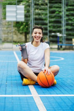 young attractive woman with basketball ball on court