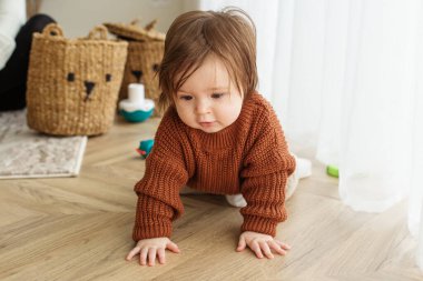 Küçük çocuk odada yerde oyuncaklarla oynuyor. Çocukluk, anaokulu ve gelişim konsepti. Kahverengi kazak
