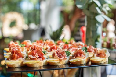 catering buffet table with snacks and appetizers. Set of canaps with jamon, bruschetta, pear and cheese and mint