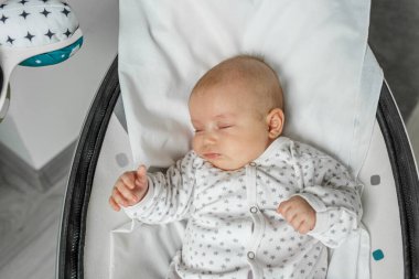 Adorable baby sleeps in baby swing in room. Newborn concept. Close up