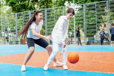 Concept of sports, hobbies and healthy lifestyle. Young people playing basketball on playground outdoors