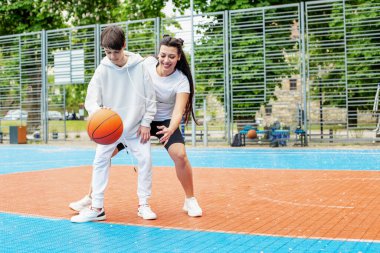 Concept of sports, hobbies and healthy lifestyle. Young people playing basketball on playground outdoors