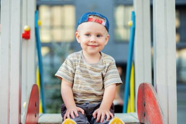 İki yaşındaki tatlı bir çocuk yaz zamanı oyun parkında slaytla oynuyor. Çocuk anaokulunun bahçesinde oynuyor. Aktif çocuk renkli kayıyor ve sallanıyor.