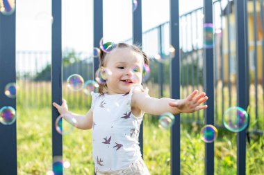 Baby toddler playing with bubbles outdoors. Having fun. Concept of childhood, family and love