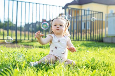 Baby toddler playing with bubbles outdoors. Having fun. Concept of childhood, family and love