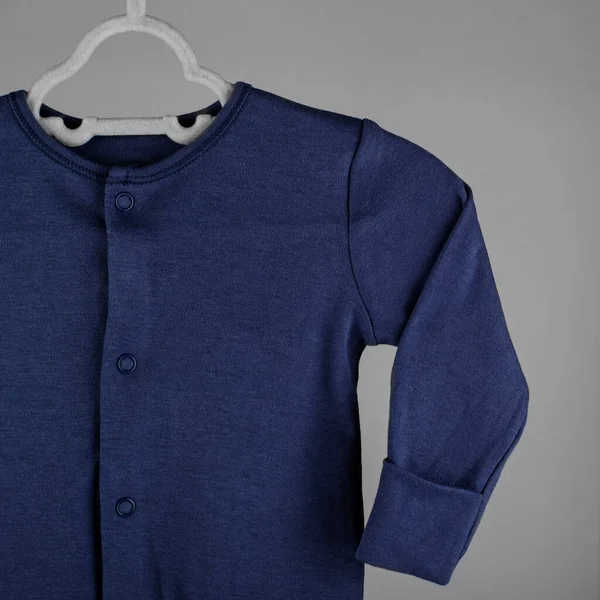 Dark blue clothes for a newborn hanging on a hanger. The concept of clothes, motherhood, fashion and newborn.