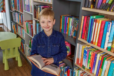 Concept of studying, back to school and education. Child schoolboy reading book in library or bookstore.