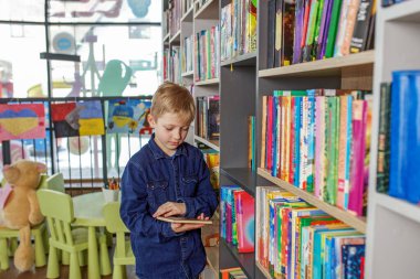 Concept of studying, back to school and education. Child schoolboy reading book in library or bookstore.