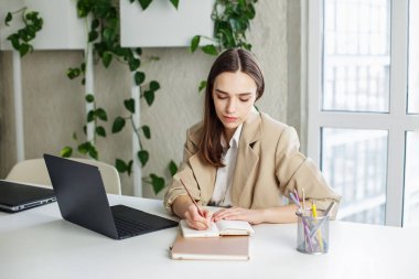 Modern yeşil ofisin masasında not defterine Freelancer yazıyor. İş, öğrenim, iş ve para kazanma kavramı.