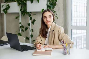 Modern yeşil ofisin masasında not defterine Freelancer yazıyor. İş, öğrenim, iş ve para kazanma kavramı.