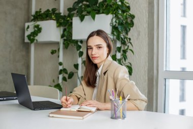 Modern yeşil ofisin masasında not defterine Freelancer yazıyor. İş, öğrenim, iş ve para kazanma kavramı.