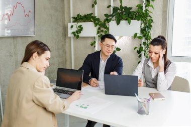 Çok ırklı iş adamları ofis toplantılarında şirket iflası yüzünden hayal kırıklığına uğradılar. Bitkileri olan modern ofis.