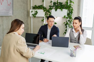 Çok ırklı iş adamları ofis toplantılarında şirket iflası yüzünden hayal kırıklığına uğradılar. Bitkileri olan modern bir ofis. İş konsepti, girişimciler ve beyin fırtınası.