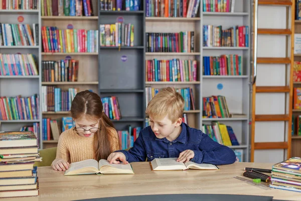Малі Школярі Разом Читають Книжки Сидячи Столом Бібліотеці Хлопчик Дівчинка — стокове фото