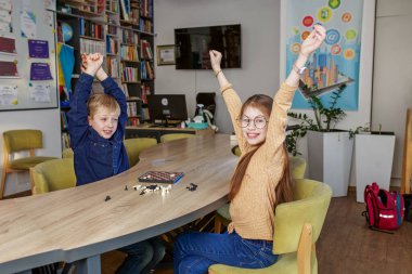 Beyaz erkek ve kız dama oynuyorlar, okulda masada birlikte oturuyorlar. Küçük arkadaş canlısı sınıf arkadaşları.