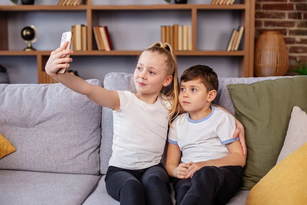 兄弟姉妹は スマートフォンで面白いメディアを見て オンラインゲームをプレイし インターネット上で学習アプリを使用しています 親の管理 — ストック写真