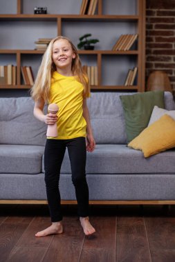 Evde şarkı söyleyip dans eden çocuk, eğlence ve eğitim konsepti, kapalı alanda.