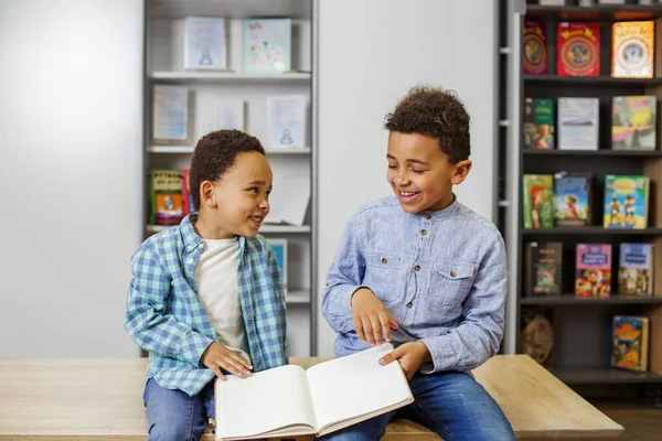 Two African American children are reading book, studying at school and having fun. Back to school. Friendship, family, childhood and study concept.