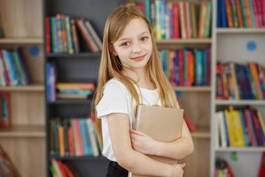 Çocuk öğrenmek ya da okumak için kitapçıdan kitaplar satın alır. Okul kütüphanesinde kitap seçen bir kız. Günlük okumanın faydaları.