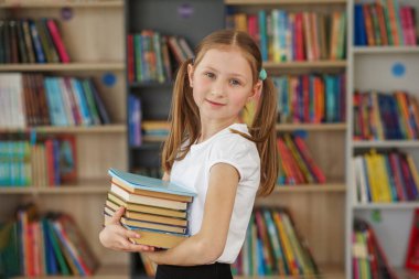 Çocuk öğrenmek ya da okumak için kitapçıdan kitaplar satın alır. Okul kütüphanesinde kitap seçen bir kız. Günlük okumanın faydaları.