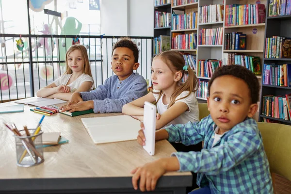 クラスメイトは教室で勉強する 学校に戻る 図書館や教室のテーブルで多民族の学生の研究や書き込み — ストック写真