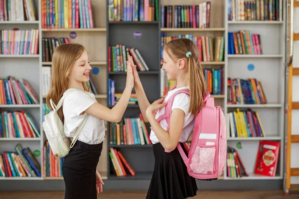夏休みの後 バックパックを持っている2人の子供たちが学校の図書館で会い 話をする 学校に戻る — ストック写真