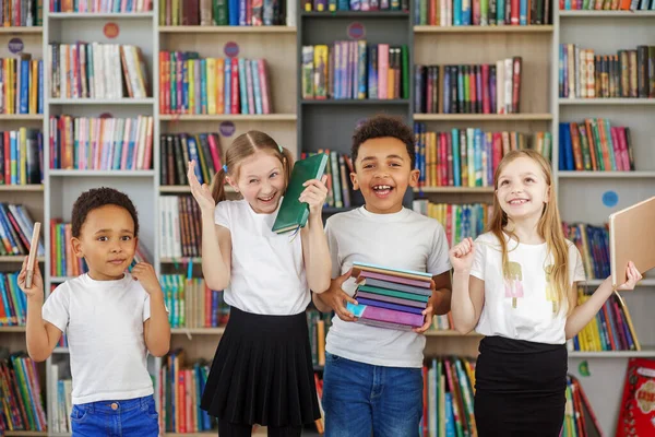 四个孩子把一堆堆书放在图书馆里 多民族同学玩得很开心 世界图书日 日常阅读的益处 — 图库照片