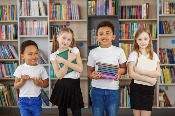 Négy Gyerek Egy Halom Könyvet Tart Könyvtárban Többnemzetiségű Osztálytársak Szórakoznak — Stock Fotó