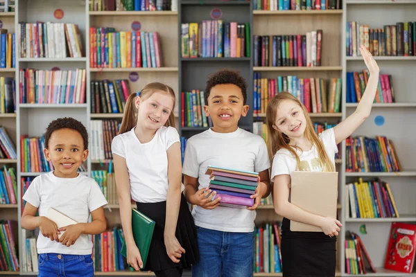 Négy Gyerek Egy Halom Könyvet Tart Könyvtárban Többnemzetiségű Osztálytársak Szórakoznak — Stock Fotó