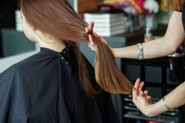 Güzellik salonunda bir kadın, kuaför saç yapıyor, uzun saçlı bir kıza saç kesiyor. Spa ve saç bakım konsepti