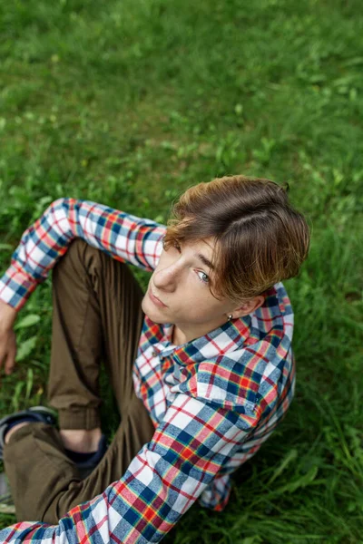 stock image Portrait of serious teenager sitting on grass in park. Gen Z. Top view. Identity development