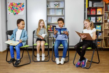 Sınıfta kitap okuyan çoklu etnik gruptan çocuklar. Eğitim, arkadaşlık ve çocukluk kavramı.