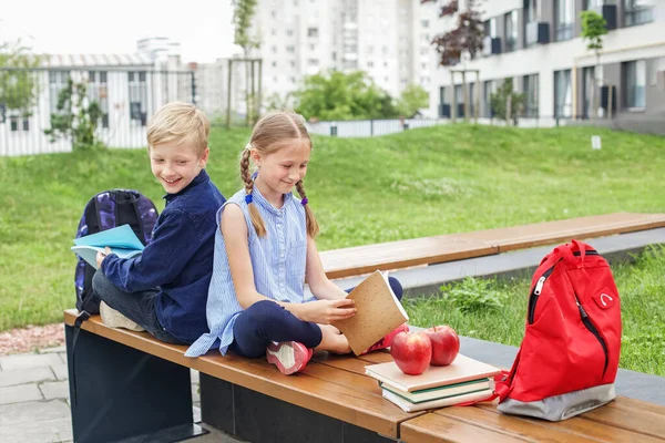 学校に戻る 2人の子供男の子と女の子一緒に本を読んで学校の庭のベンチに座って話をする — ストック写真
