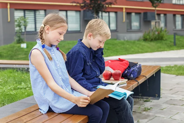 子供たちは学校の庭のベンチに座って本を読む 学校に戻る 学校の授業開始 — ストック写真