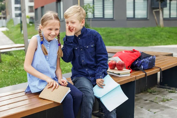 回学校去两个同学 男孩和女孩 坐在学校院子里的长椅上看书 — 图库照片