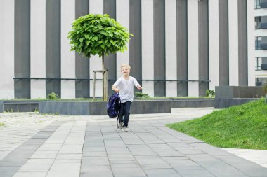 Okula dönelim. Çocuk sırt çantasıyla okula koşuyor. Çocukluk, eğitim ve okul kavramı.