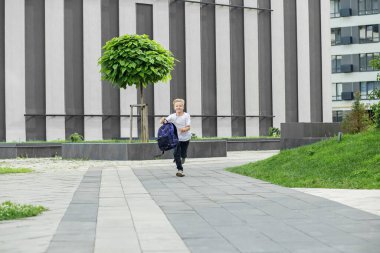 Okula dönelim. Çocuk sırt çantasıyla okula koşuyor. Çocukluk, eğitim ve okul kavramı.