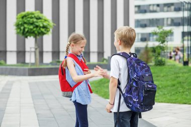 Arkadaşlarla tanışmak. Okula dönelim. Sırt çantalı iki çocuk okulun yanında karşılaştı. Öğrenme, arkadaşlık ve çocukluk kavramı.